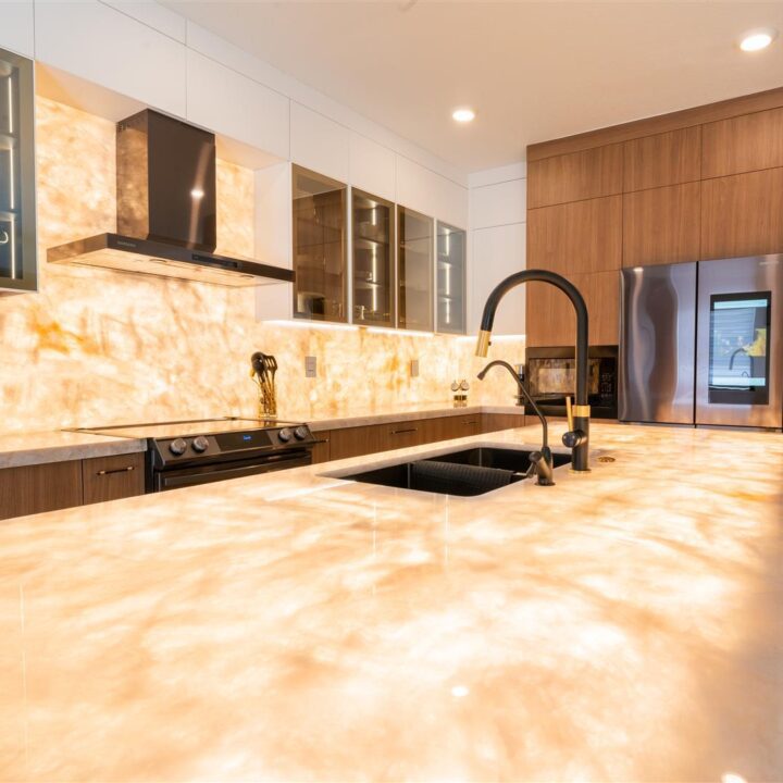 A kitchen with marble counter tops and stainless steel appliances.