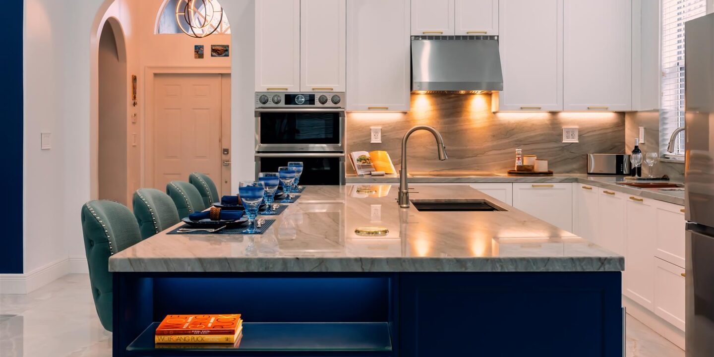 A kitchen with a blue island and white cabinets.