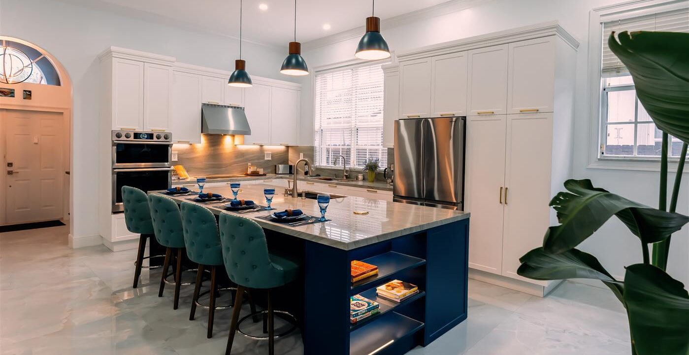 A white kitchen with a blue island and chairs.