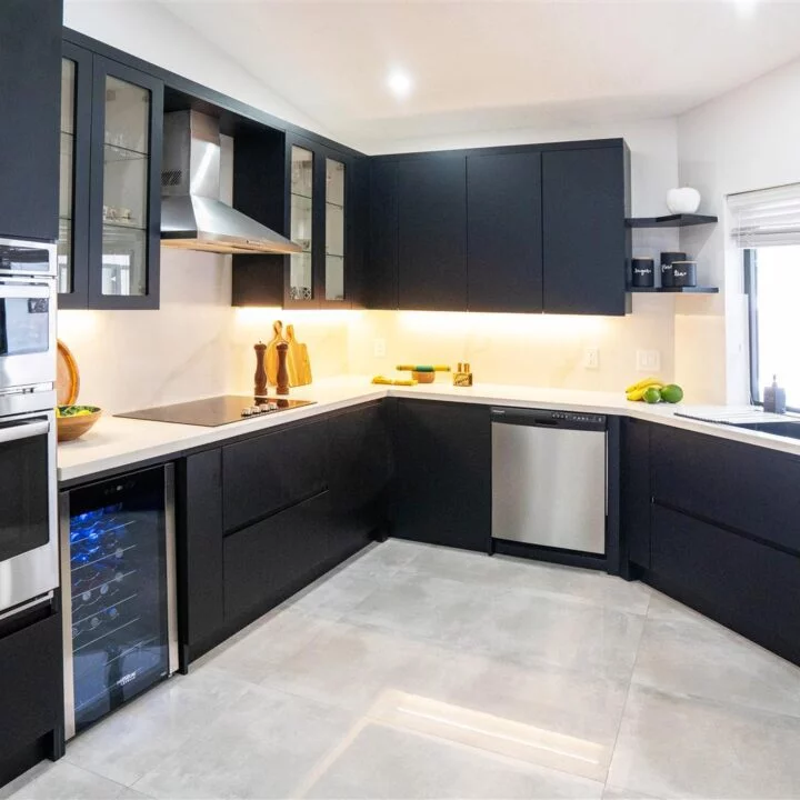 A Pembroke Pines Residence custom kitchen with black cabinets and stainless steel appliances.