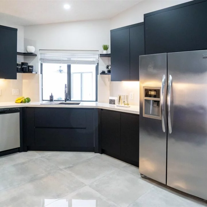 A custom kitchen in the Pembroke Pines Residence featuring black cabinets and stainless steel appliances.